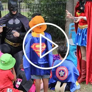 Video thumbnail showing children dressed as superheroes interacting with adults in costume during a playful outdoor event symbolising imagination, empowerment, and community impact.