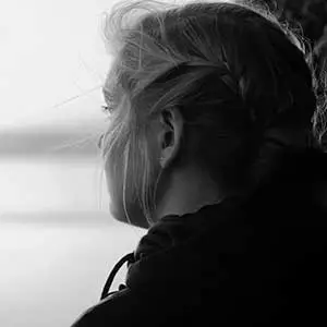 Teen girl gazing thoughtfully out a window, capturing quiet strength and vulnerability.
