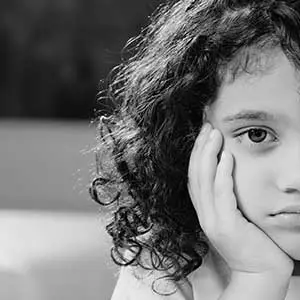 Sad child resting on hand, symbolising the impact of educational instability